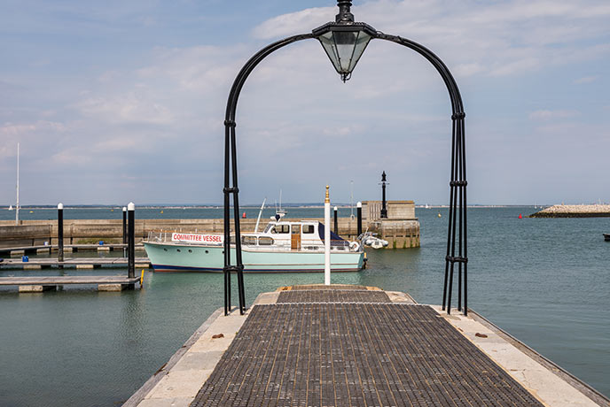 Looking down the pier of Cowes Harbour at a boat